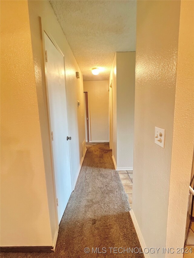 corridor featuring light carpet and a textured ceiling