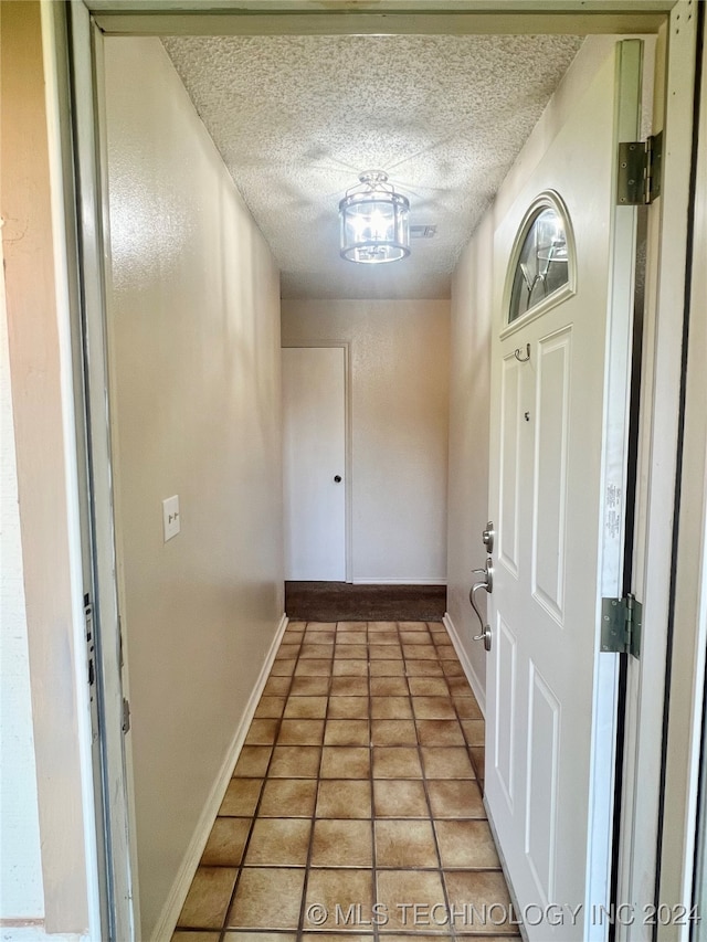 entryway with a textured ceiling and tile patterned flooring