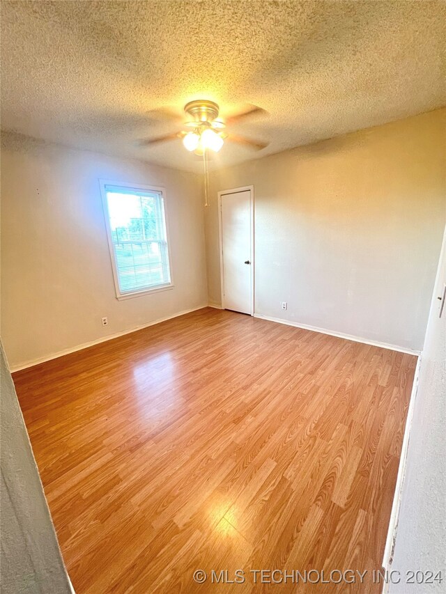 spare room with ceiling fan, a textured ceiling, and light hardwood / wood-style flooring