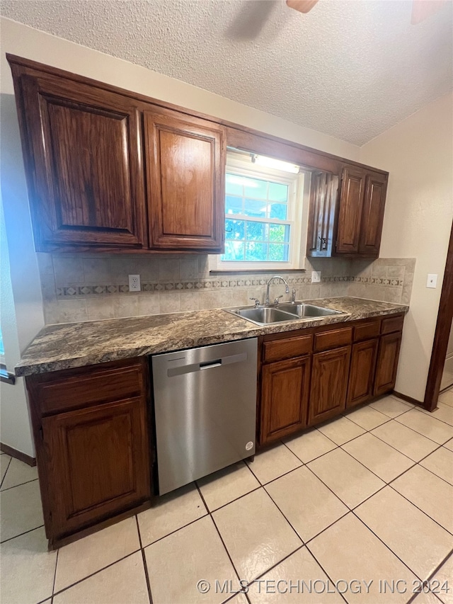 kitchen with a textured ceiling, backsplash, light tile patterned floors, dishwasher, and sink