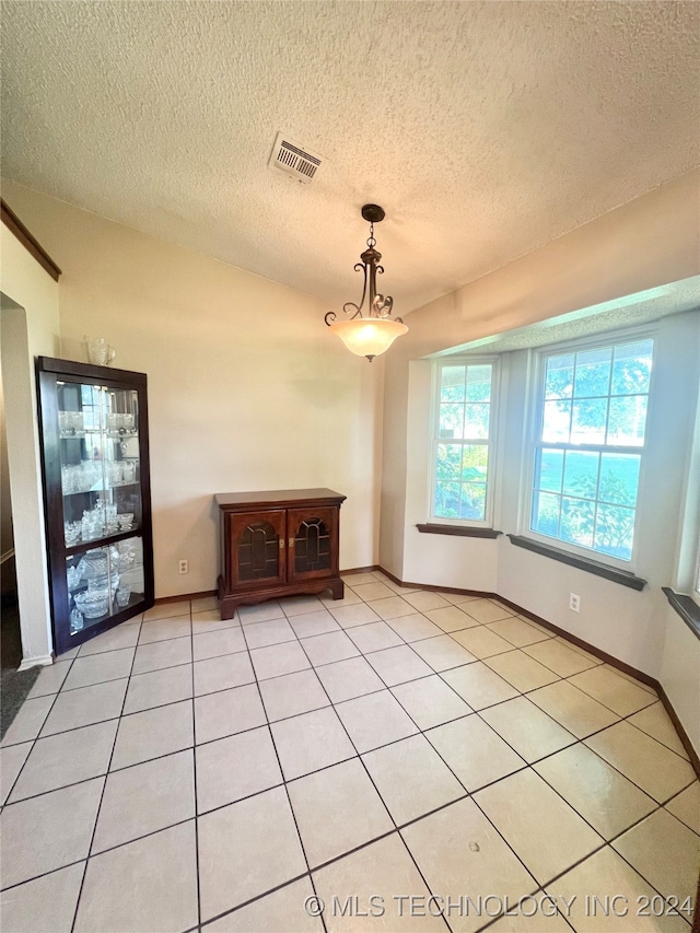 unfurnished dining area with light tile patterned floors and a textured ceiling