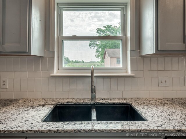 details featuring sink, decorative backsplash, and light stone countertops