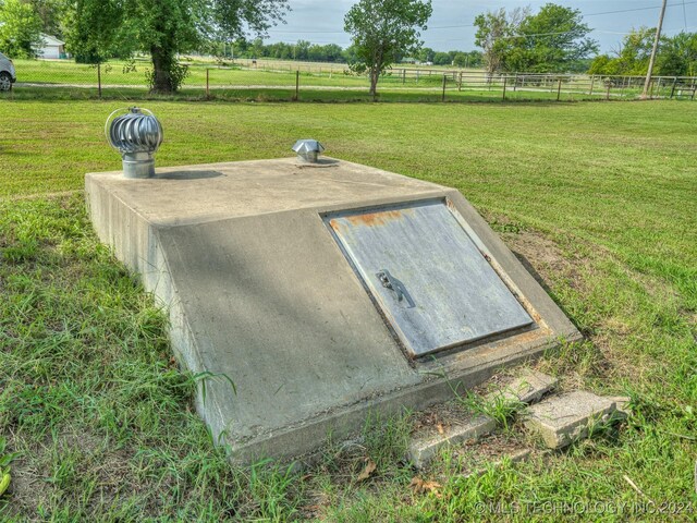 entry to storm shelter with a lawn and a rural view