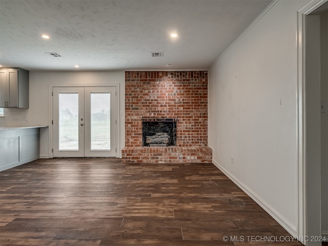 unfurnished living room with ornamental molding, dark hardwood / wood-style flooring, french doors, and a brick fireplace