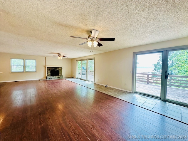 unfurnished living room featuring plenty of natural light, a stone fireplace, and light hardwood / wood-style flooring