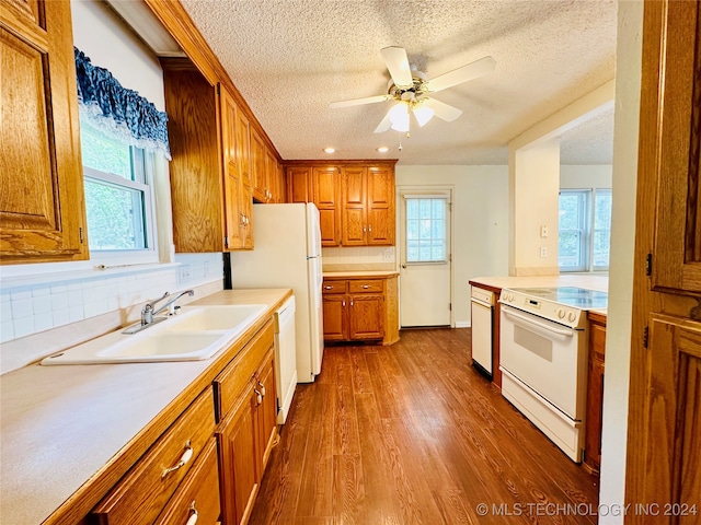 kitchen with a wealth of natural light, white appliances, dark wood-type flooring, and sink