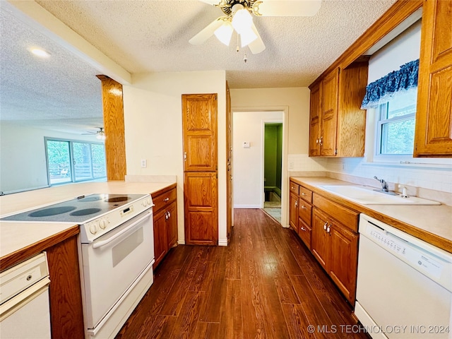 kitchen featuring sink, dark wood-type flooring, a textured ceiling, and white appliances