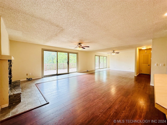 unfurnished living room featuring ceiling fan, wood-type flooring, a textured ceiling, and a fireplace