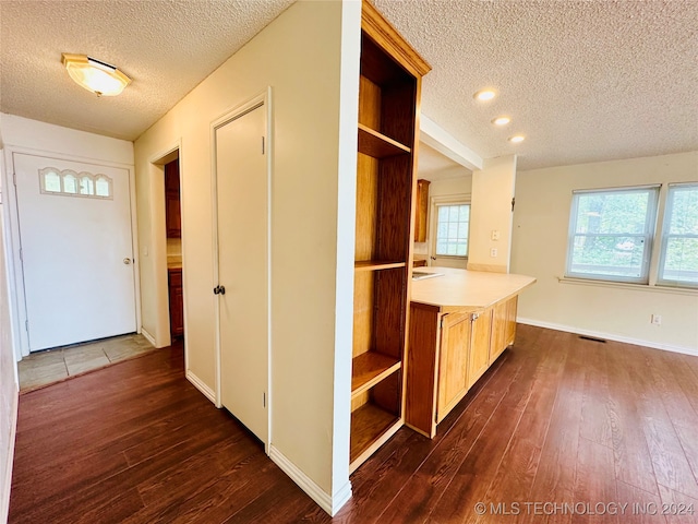 kitchen featuring kitchen peninsula, a textured ceiling, and dark wood-type flooring