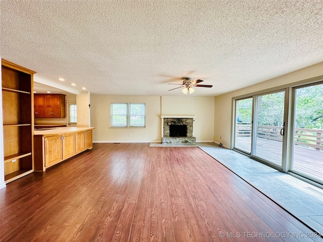 unfurnished living room featuring a fireplace, plenty of natural light, a textured ceiling, and dark wood-type flooring