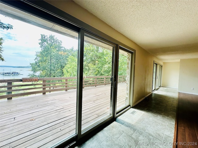 entryway with tile patterned floors, a textured ceiling, and a water view