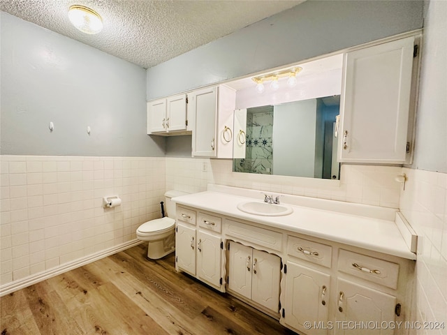 bathroom with tile walls, a textured ceiling, vanity, and toilet