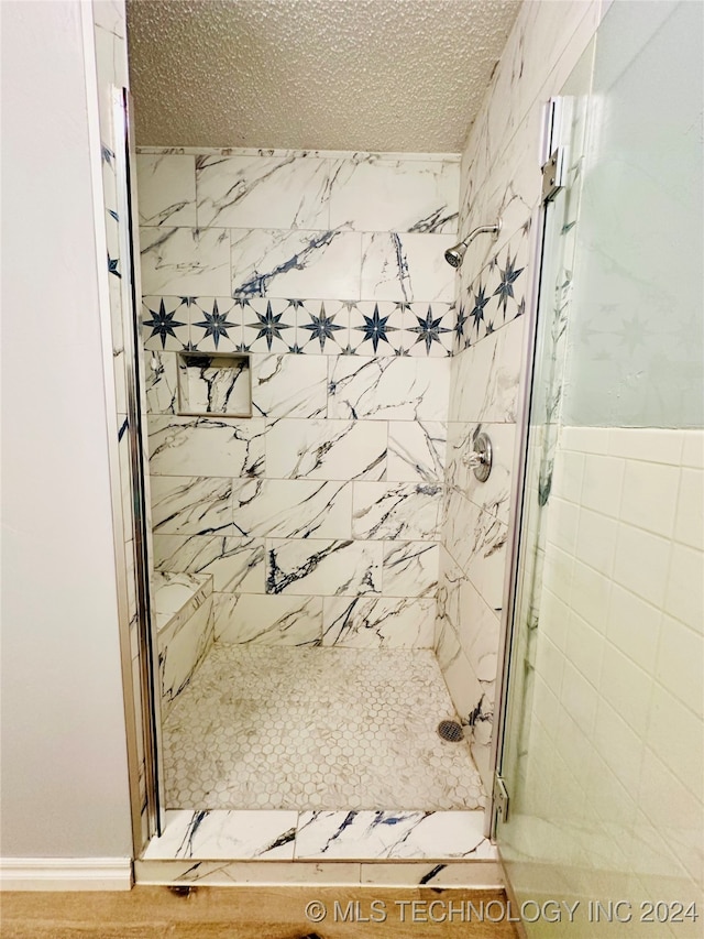 bathroom with a shower with shower door and a textured ceiling