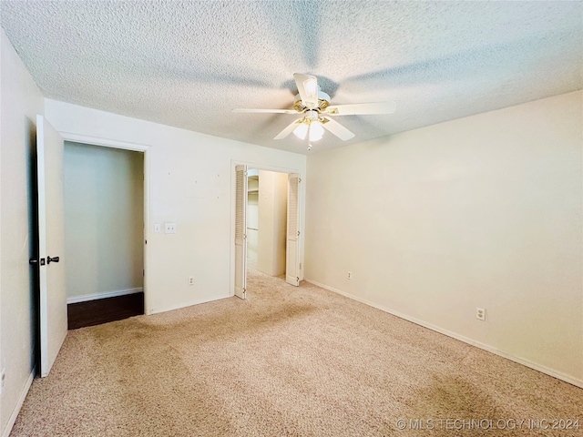 unfurnished bedroom with ceiling fan, light colored carpet, and a textured ceiling