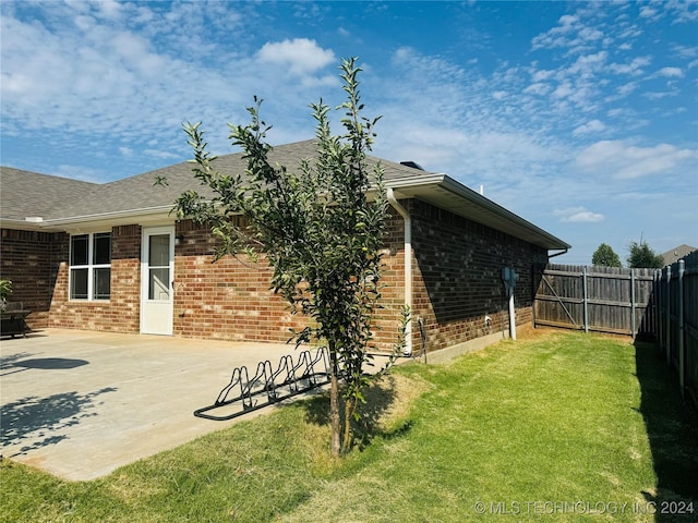 exterior space featuring a yard, brick siding, a patio area, and a fenced backyard