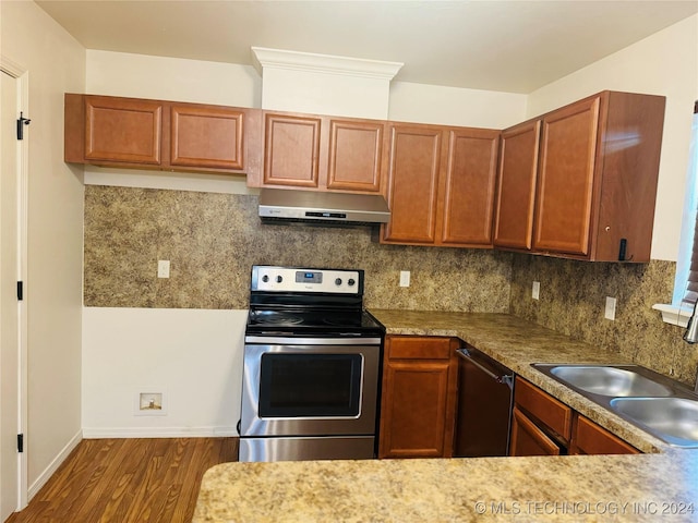 kitchen with dark wood finished floors, appliances with stainless steel finishes, a sink, extractor fan, and backsplash