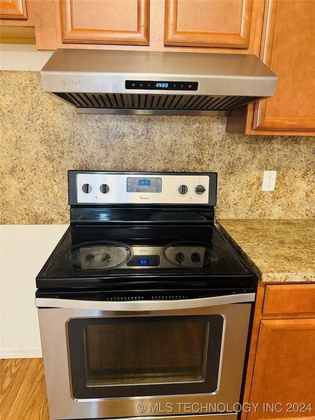 interior details featuring tasteful backsplash, brown cabinetry, electric stove, and exhaust hood