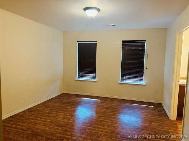 empty room with baseboards, visible vents, and wood finished floors