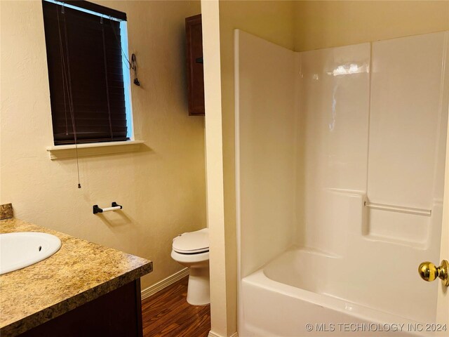 full bathroom with shower / washtub combination, hardwood / wood-style flooring, toilet, and vanity