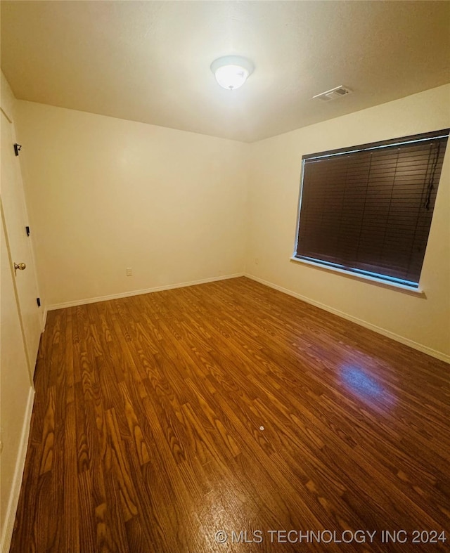 empty room with baseboards, visible vents, and wood finished floors