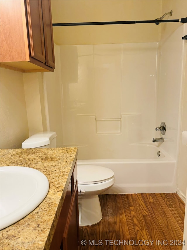 full bathroom with hardwood / wood-style flooring, shower / bathtub combination, vanity, and toilet