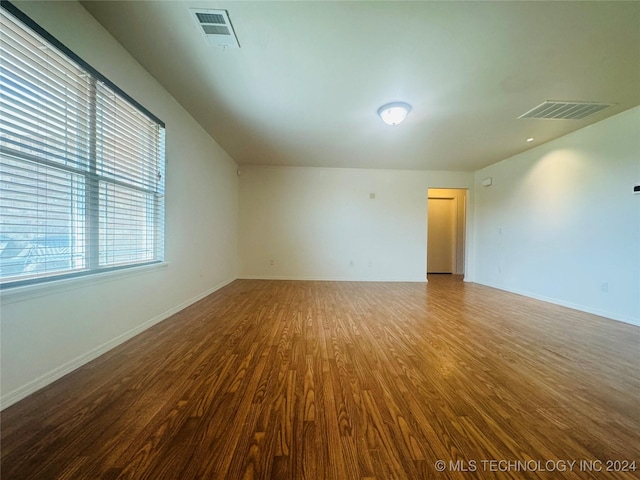 unfurnished room featuring wood finished floors, visible vents, and baseboards