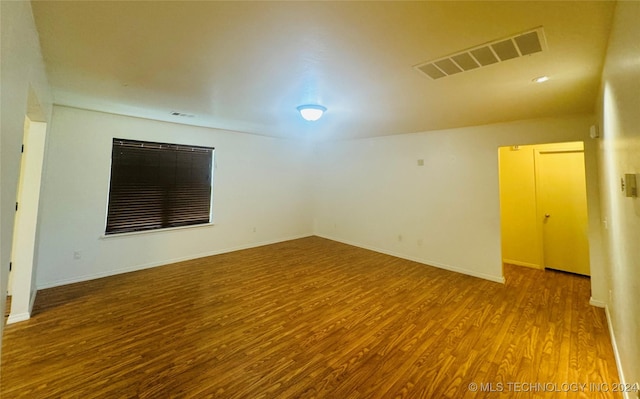 unfurnished room with baseboards, visible vents, and wood finished floors