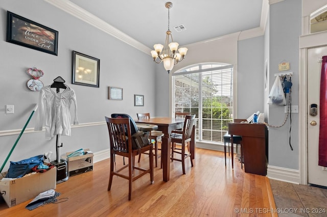 dining room with ornamental molding, light wood-type flooring, visible vents, and a notable chandelier