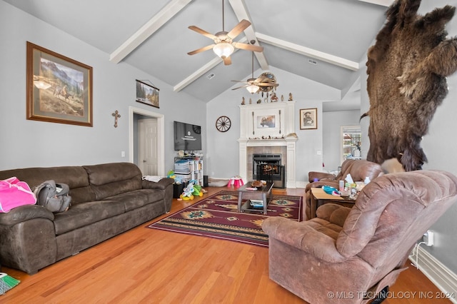 living area featuring a tiled fireplace, ceiling fan, wood finished floors, high vaulted ceiling, and beam ceiling