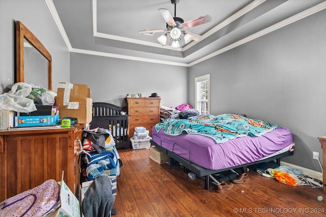 bedroom with baseboards, a raised ceiling, hardwood / wood-style flooring, ceiling fan, and ornamental molding