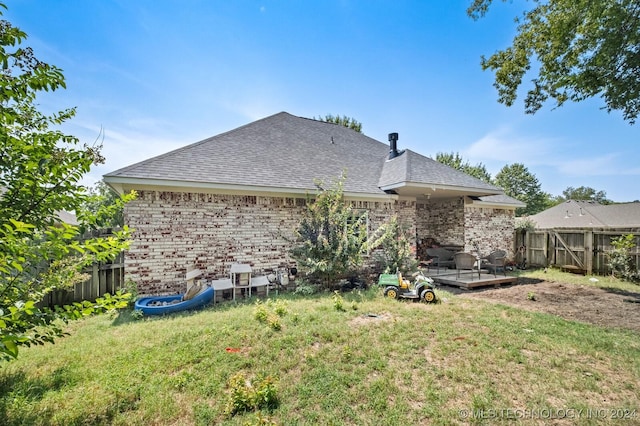 back of property featuring brick siding, a lawn, fence, and a wooden deck