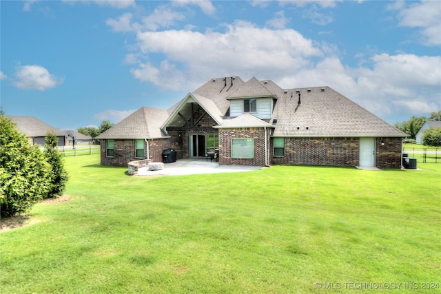 rear view of property featuring a patio, brick siding, fence, a lawn, and roof with shingles