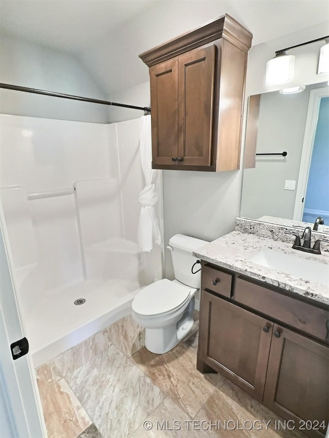 bathroom featuring toilet, a shower stall, and vanity