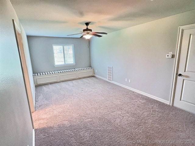 carpeted empty room with ceiling fan, visible vents, and baseboards