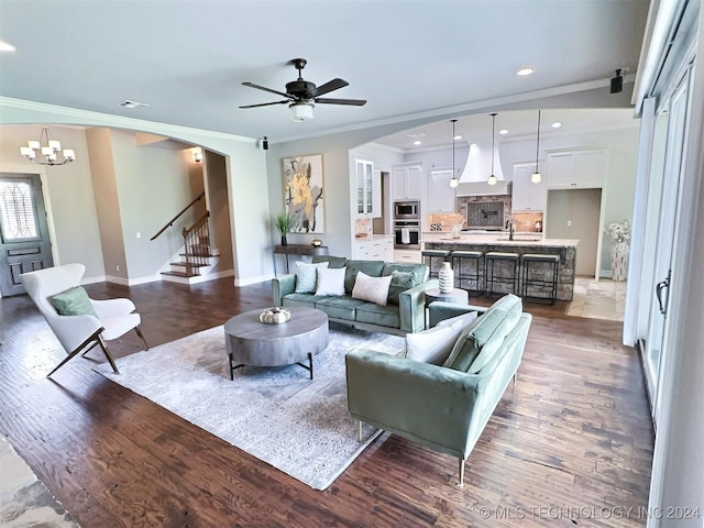 living area featuring baseboards, arched walkways, dark wood finished floors, stairs, and crown molding