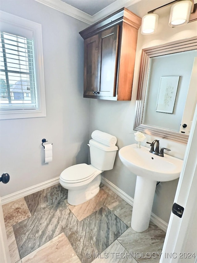 bathroom featuring ornamental molding, a sink, toilet, and baseboards