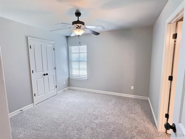 unfurnished bedroom with baseboards, ceiling fan, a closet, and light colored carpet