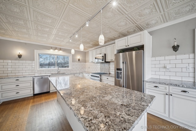 kitchen with sink, hanging light fixtures, premium appliances, a kitchen island, and white cabinets