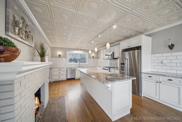 kitchen featuring pendant lighting, appliances with stainless steel finishes, a kitchen island, white cabinets, and a kitchen bar