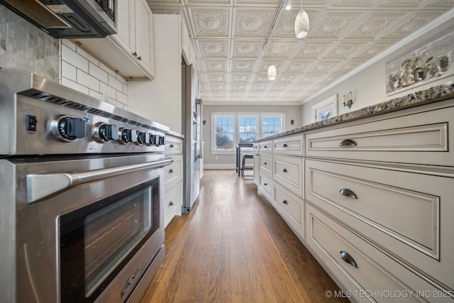 kitchen featuring range, ornamental molding, dark hardwood / wood-style floors, light stone countertops, and decorative backsplash