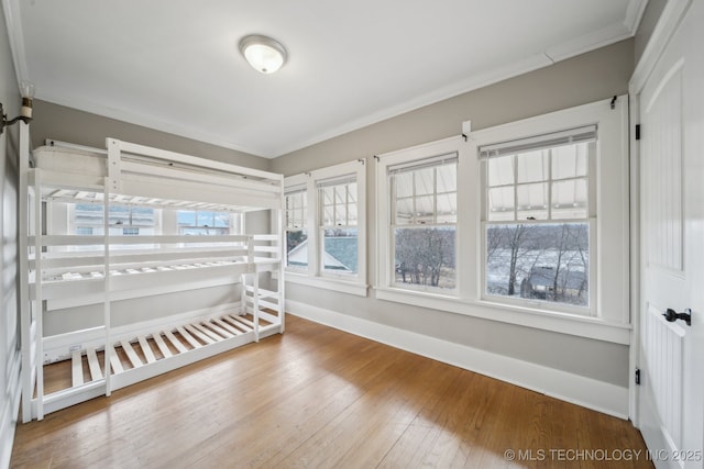 unfurnished bedroom with hardwood / wood-style floors and ornamental molding