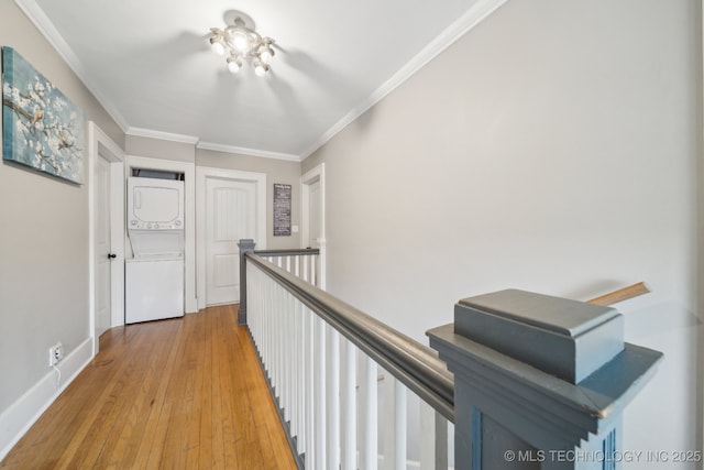 hallway with light hardwood / wood-style flooring, ornamental molding, and stacked washer / dryer