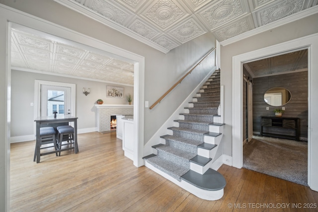 stairs featuring ornamental molding, wood-type flooring, and a fireplace