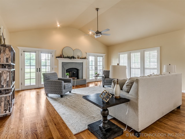 living room featuring ceiling fan, wood-type flooring, french doors, and a fireplace