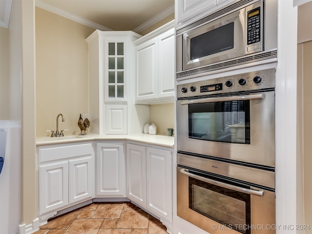 kitchen with ornamental molding, stainless steel appliances, sink, and white cabinetry