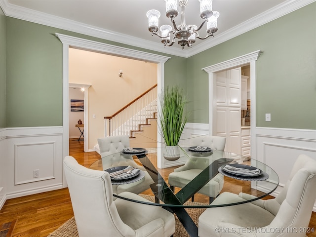 dining space featuring wood-type flooring, an inviting chandelier, and ornamental molding