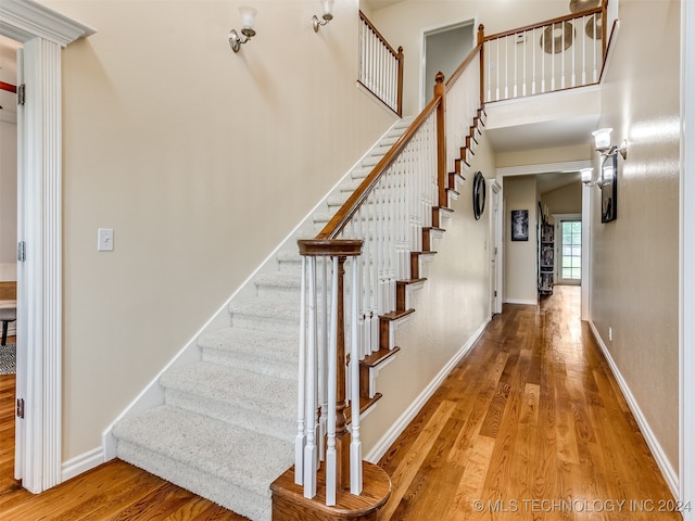 stairway with hardwood / wood-style flooring and vaulted ceiling