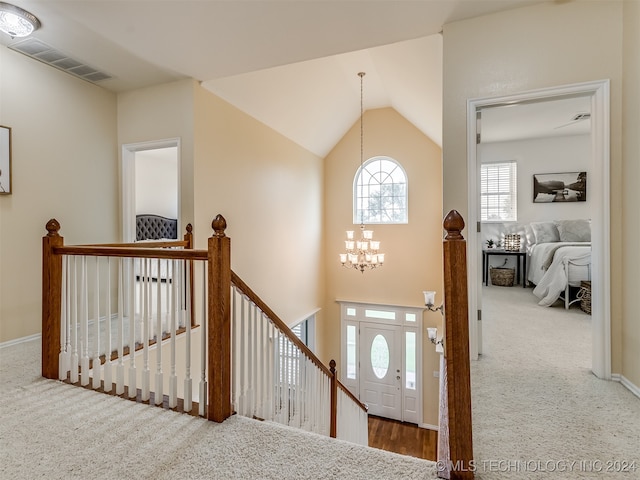 hall featuring lofted ceiling, carpet flooring, and a notable chandelier