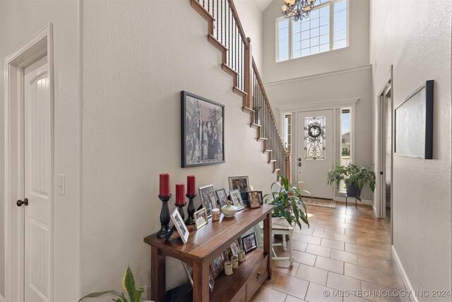 tiled foyer entrance with a towering ceiling and a notable chandelier