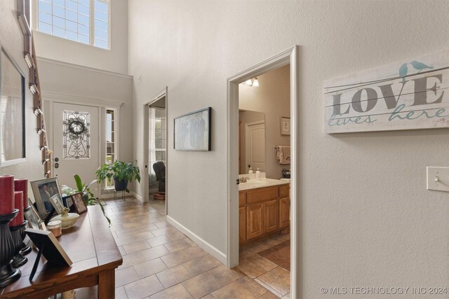 tiled entrance foyer with a towering ceiling and sink